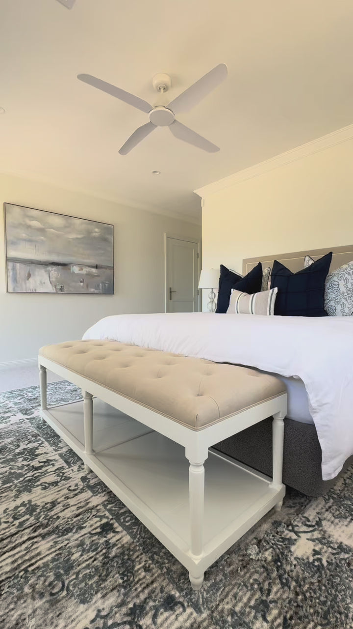 hamptons bench seat with natural linen chesterfield top with white timber base sitting at the end of the bed for storage in bedroom